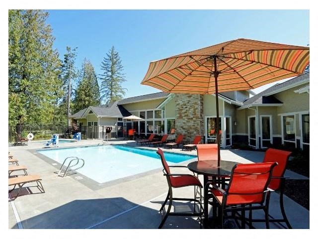 a swimming pool with a table with chairs and an umbrella
