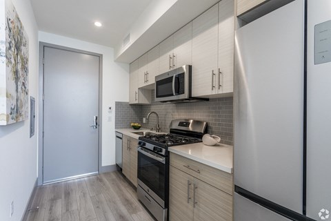 a kitchen with white cabinets and black appliances and a stainless steel refrigerator