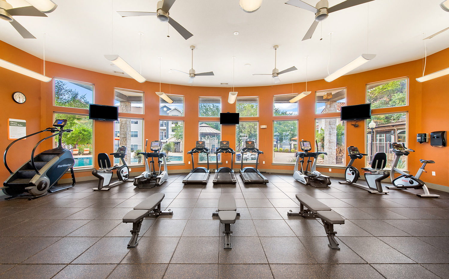 a gym with treadmills and other exercise equipment in a large room with windows