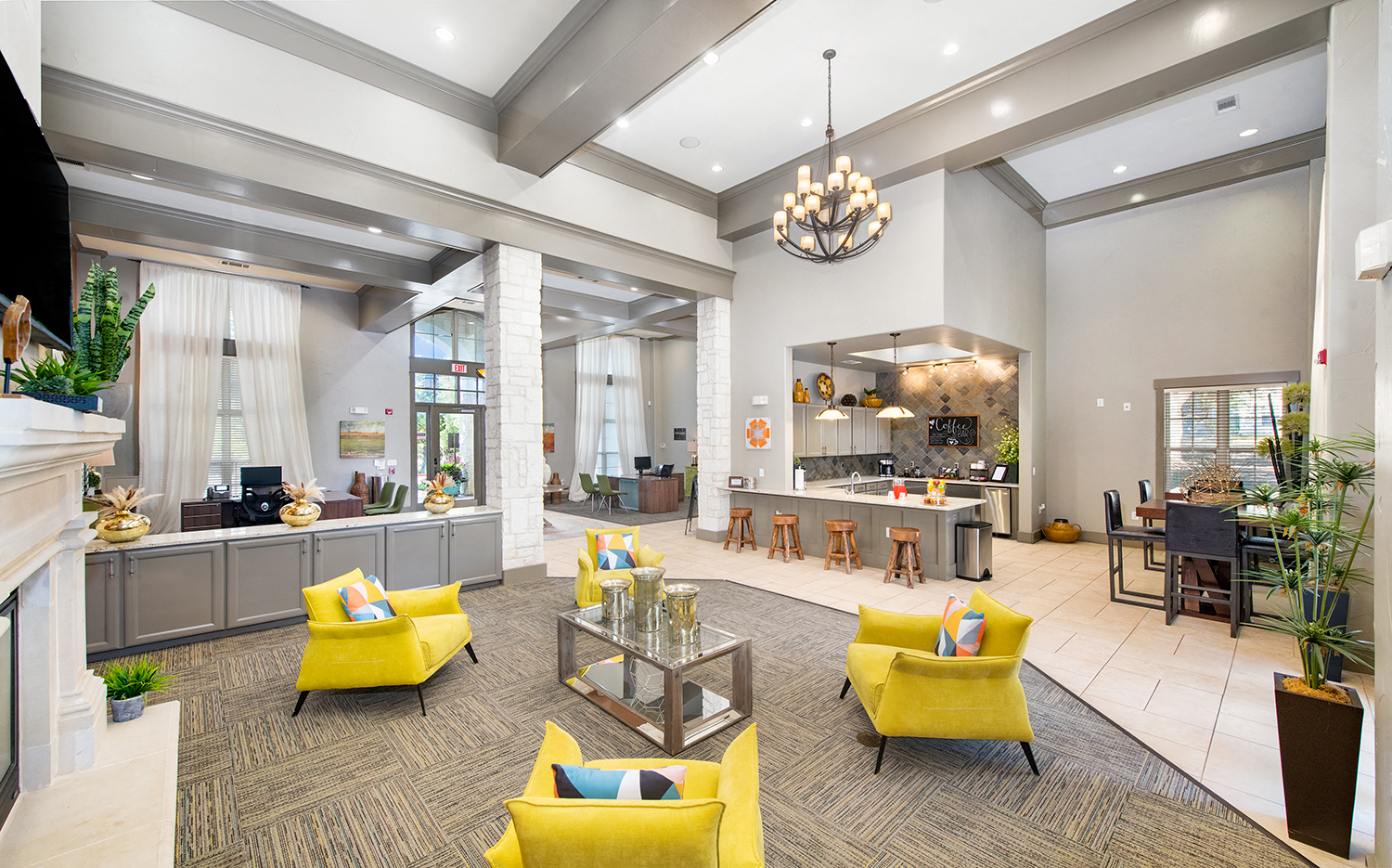 a large lobby with yellow chairs and a kitchen