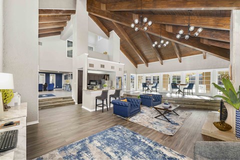 A spacious living room with a blue rug and wooden beams.