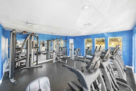 A gym with a variety of equipment including treadmills, weights, and exercise machines.