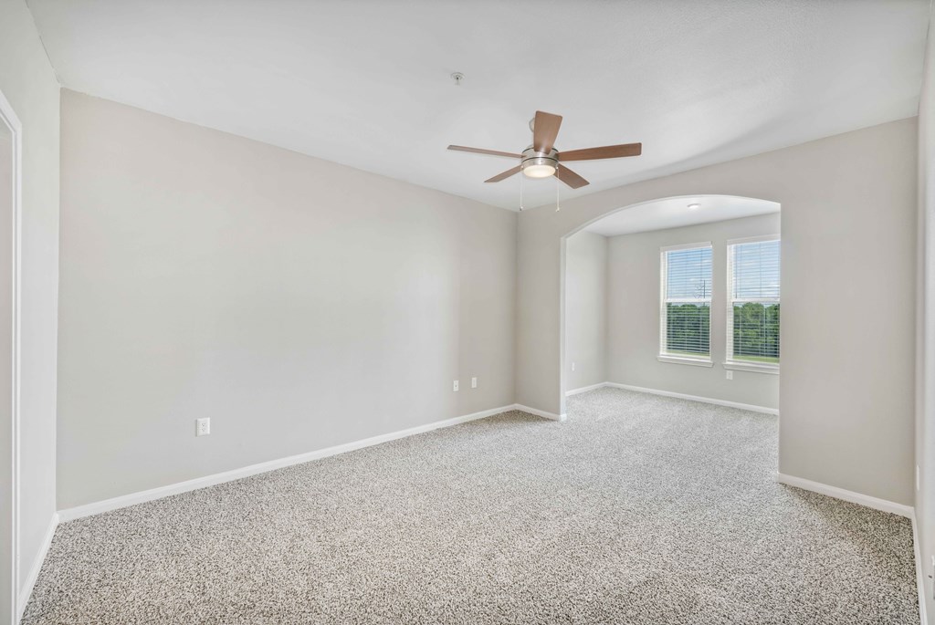 an empty living room with a ceiling fan and a window