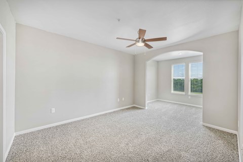 an empty living room with a ceiling fan and a window
