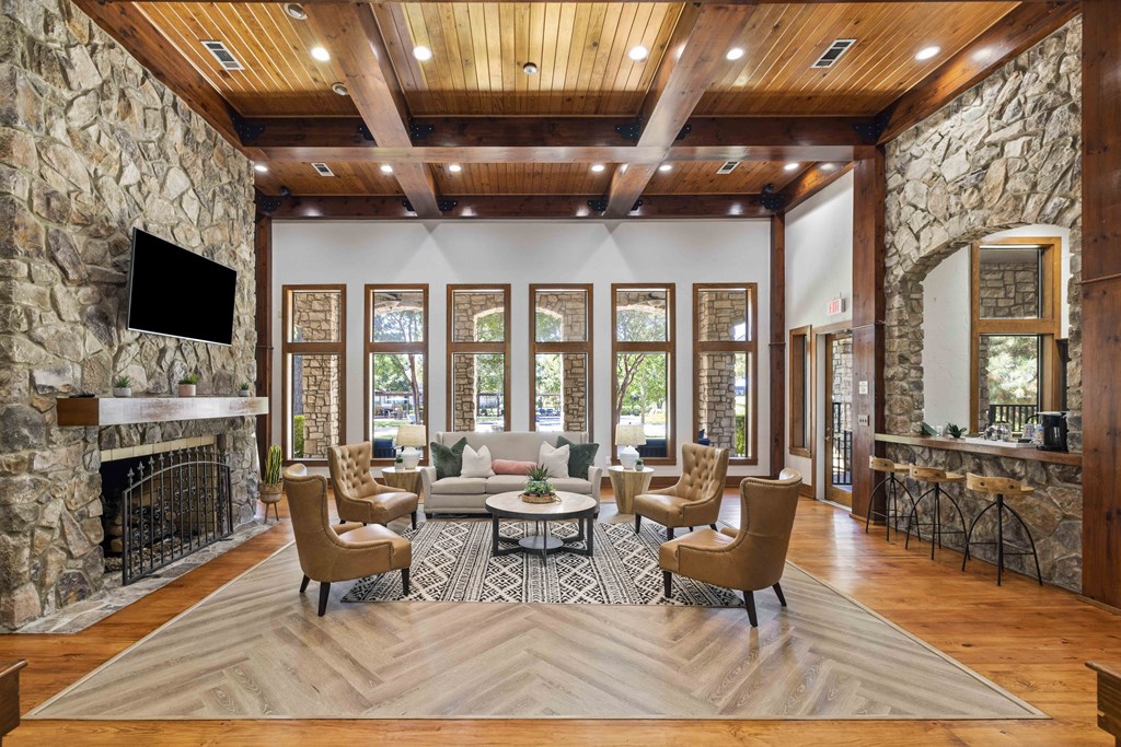 A living room with a stone fireplace and wooden ceiling.