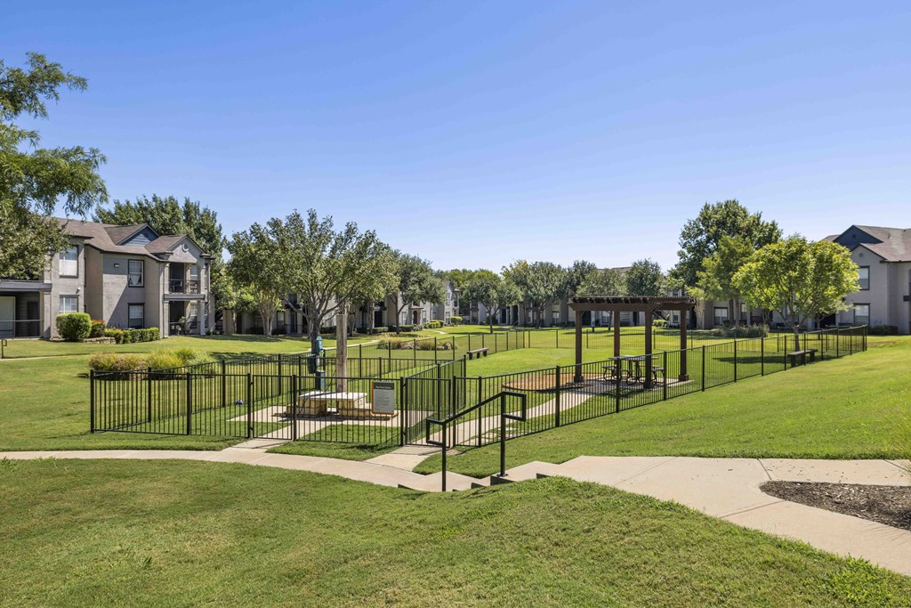 A park with a black fence and a grassy area.