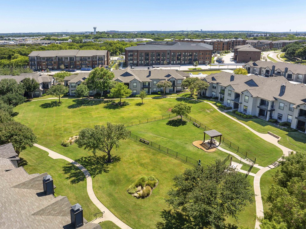 A large grassy area with a gazebo and a walking path in the middle of a residential area.