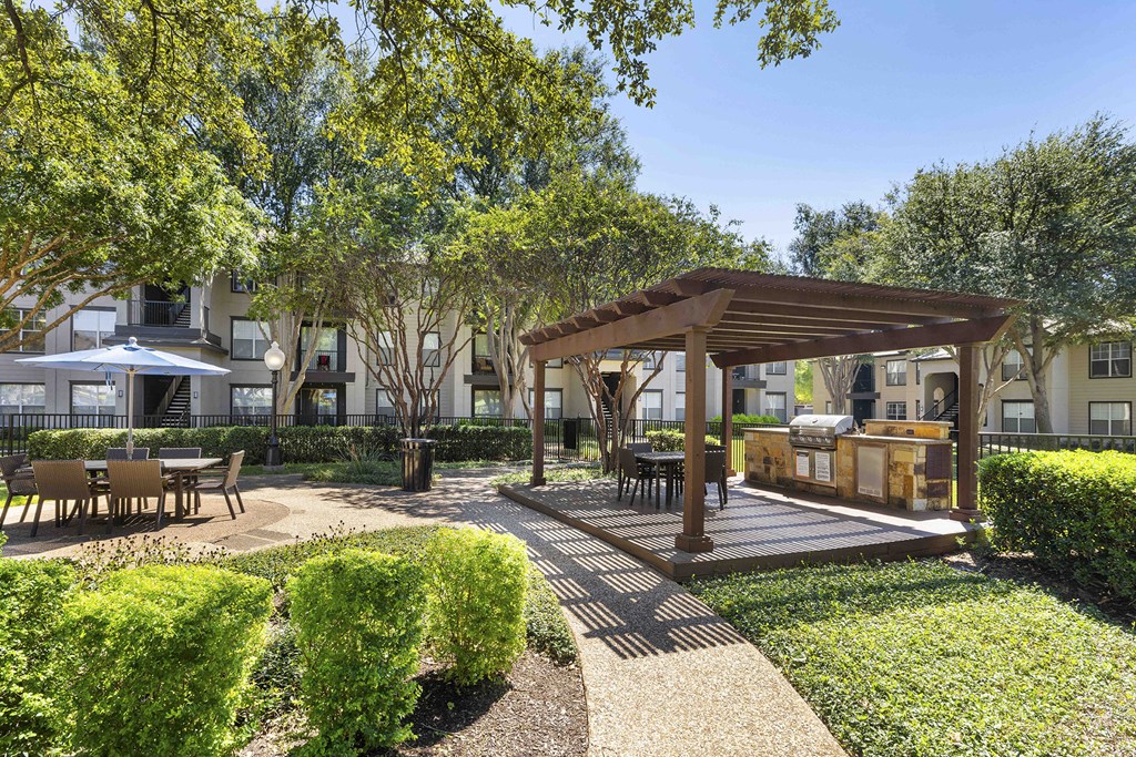 A sunny day at a park with a pavilion and a walking path.