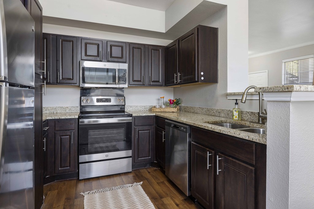 A kitchen with dark brown cabinets and stainless steel appliances.
