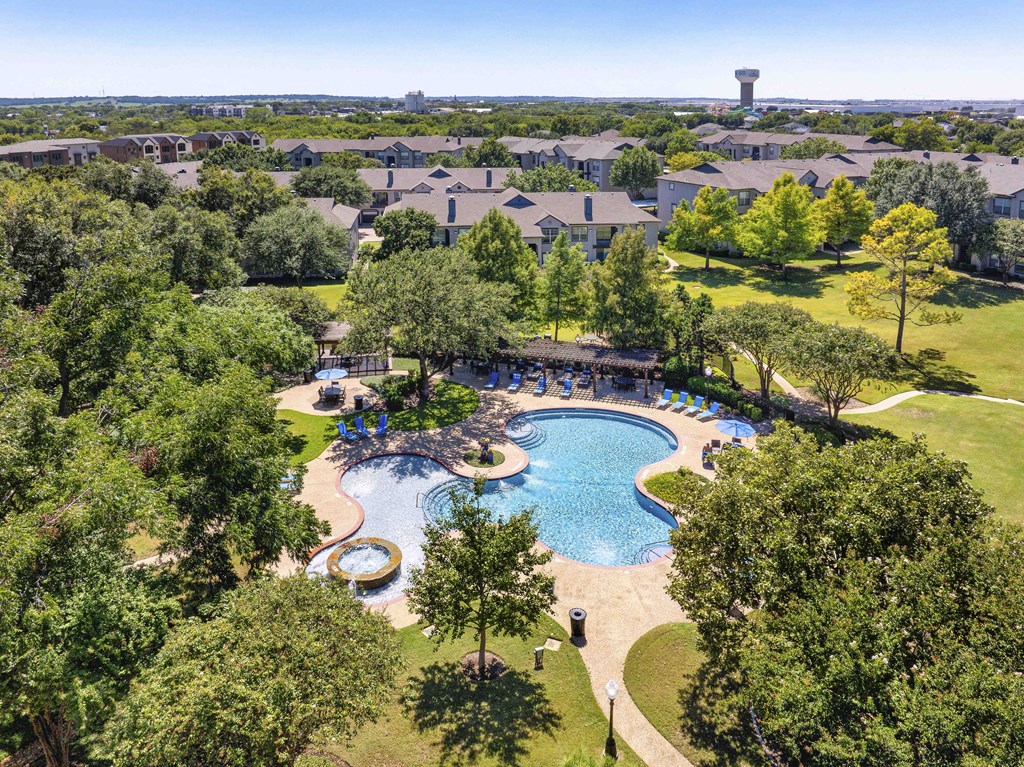 A large swimming pool surrounded by trees and a grassy area.