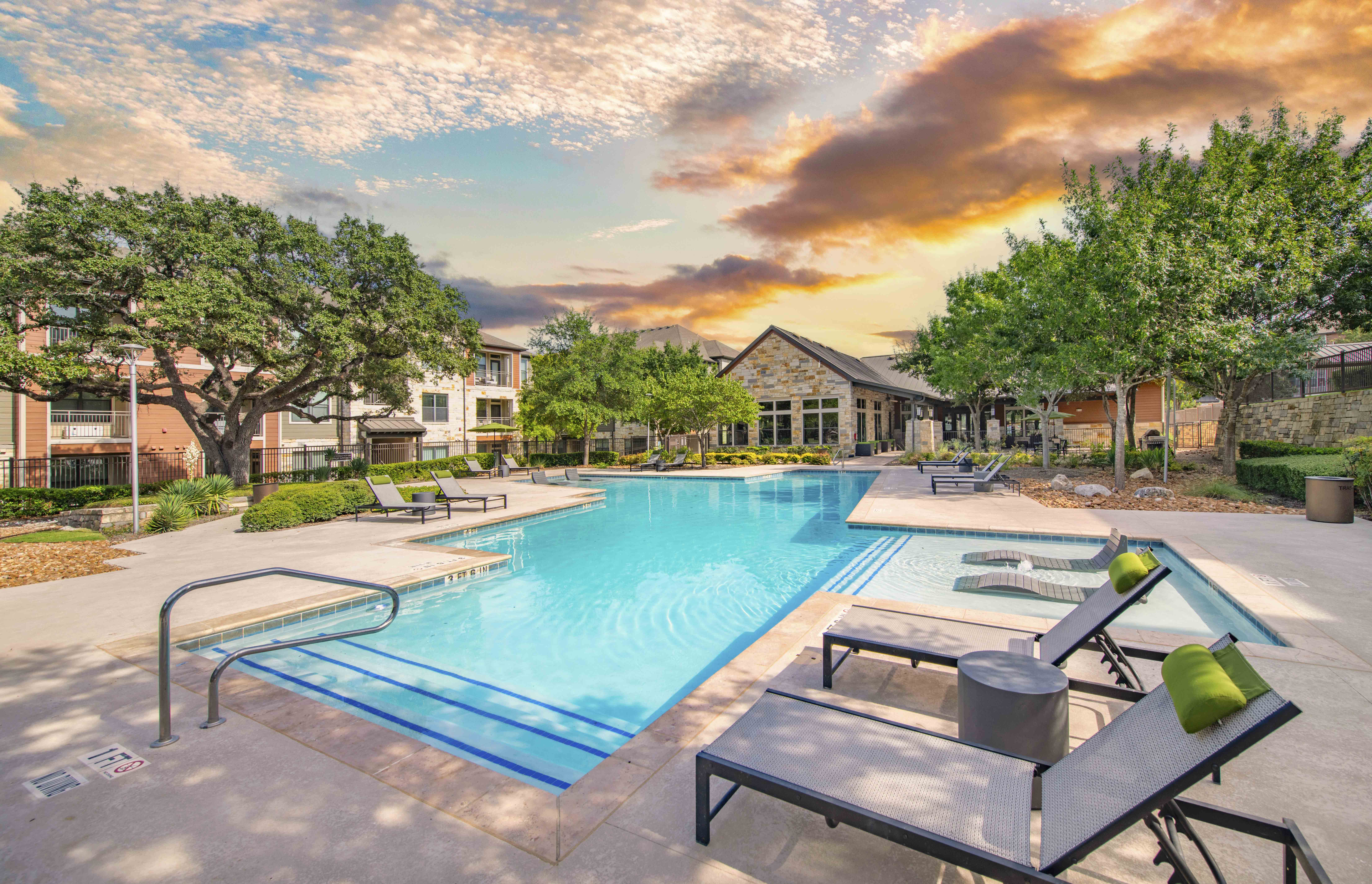 a swimming pool with tables and chairs at an apartment complex