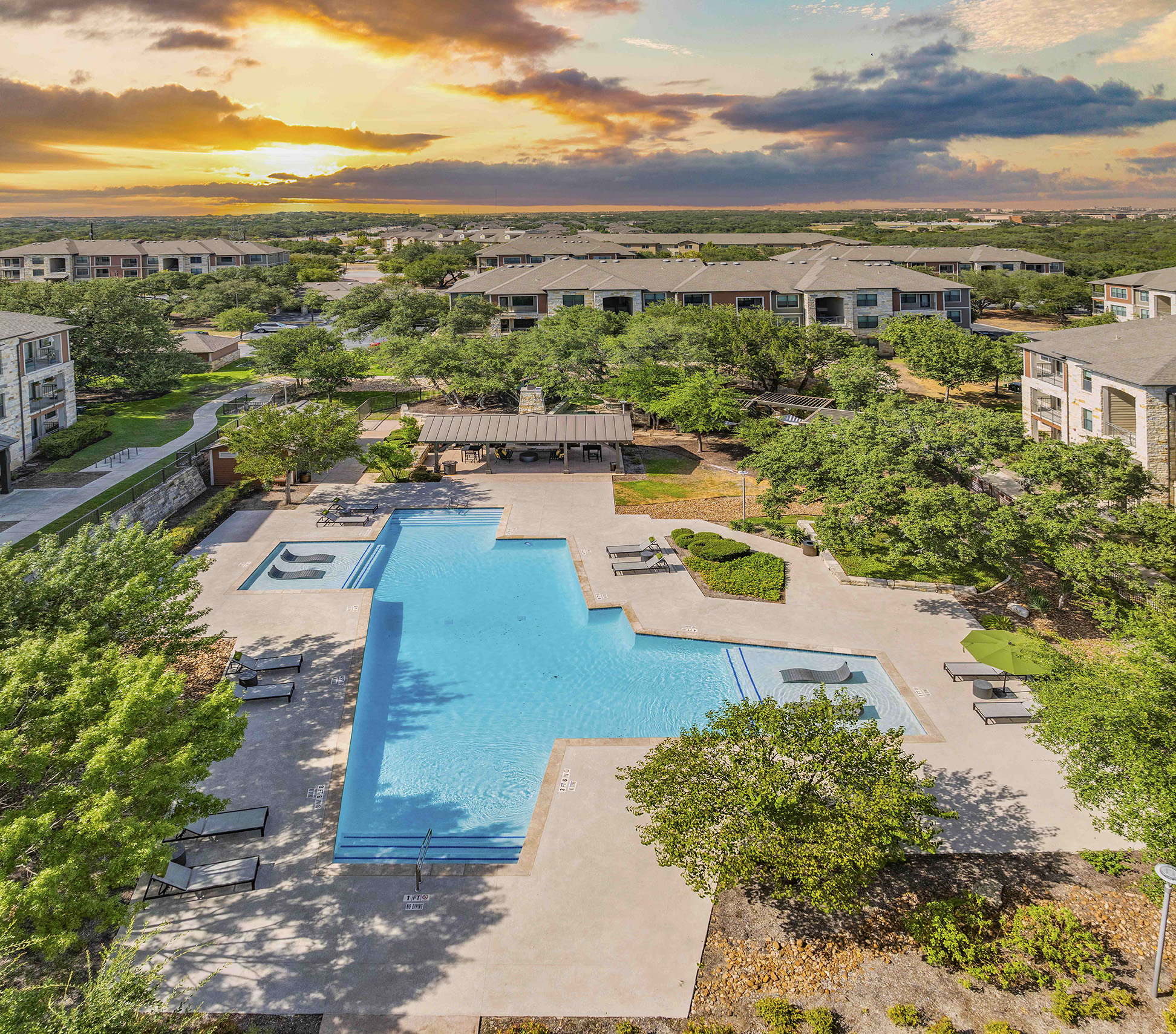 an aerial view of a swimming pool with buildings in the background