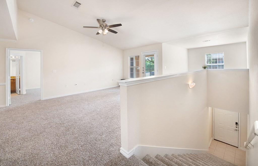 an empty living room and kitchen with a ceiling fan