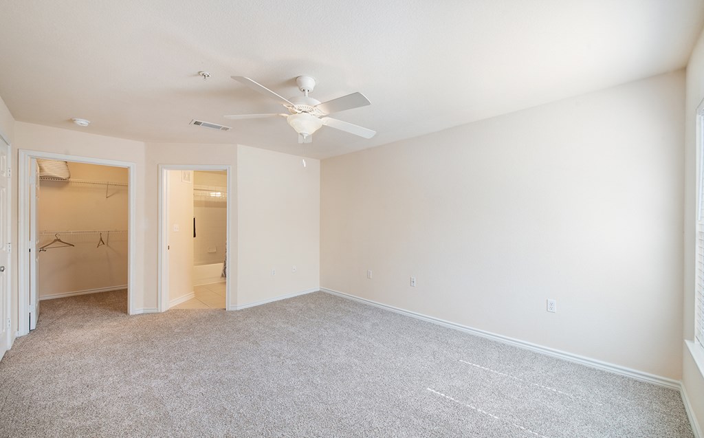 an empty living room with a ceiling fan and a closet