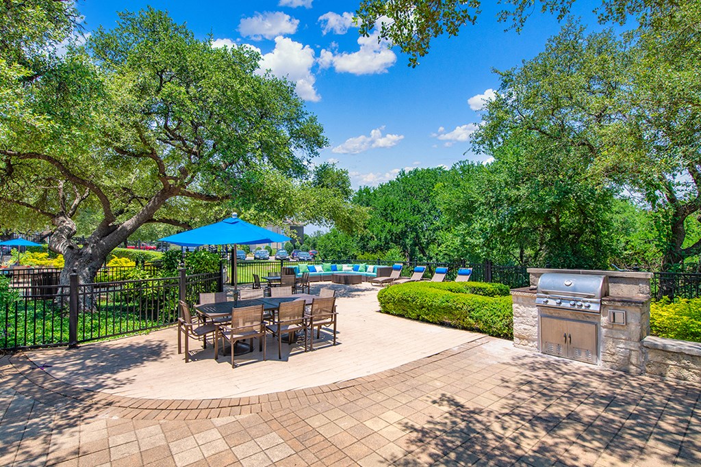 a patio with a grill and tables with umbrellas
