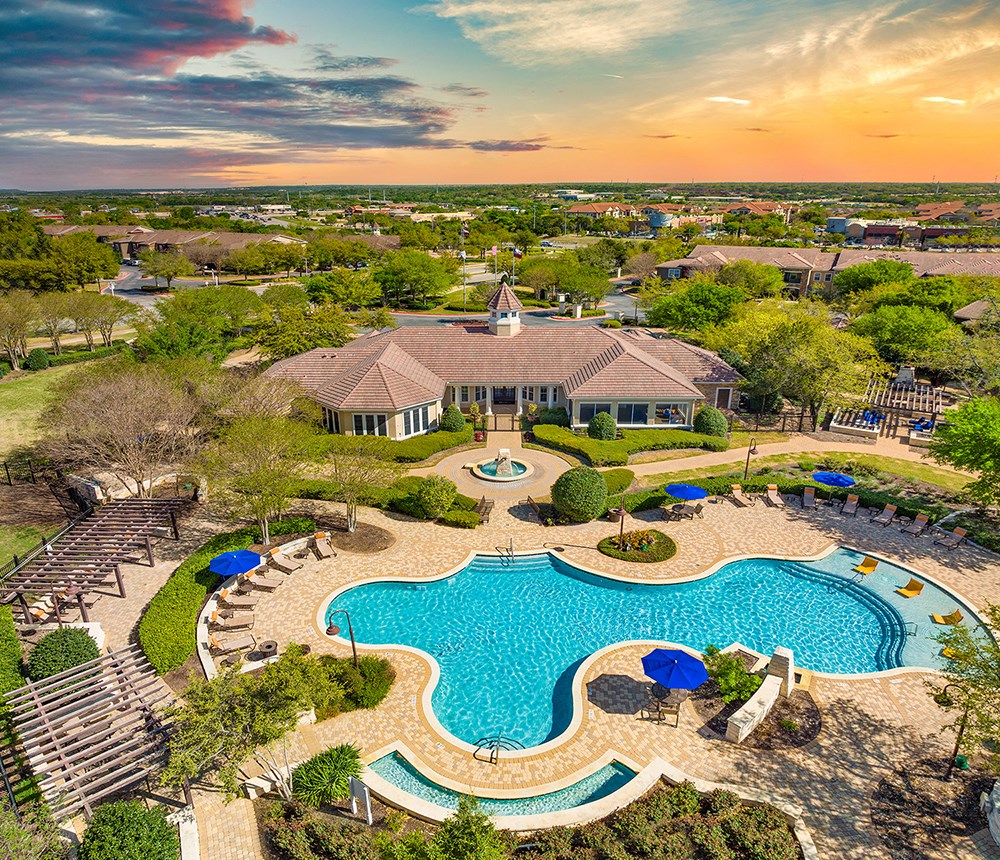 an aerial view of the pool and pool house at sunset