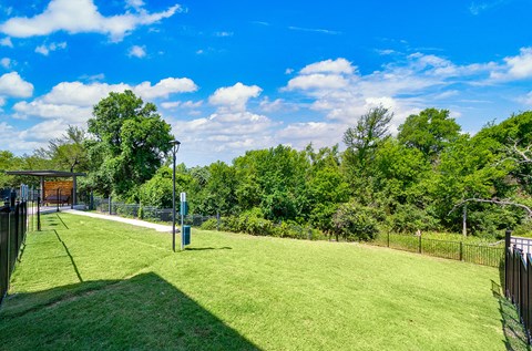 a park with a grassy field and a chain link fence