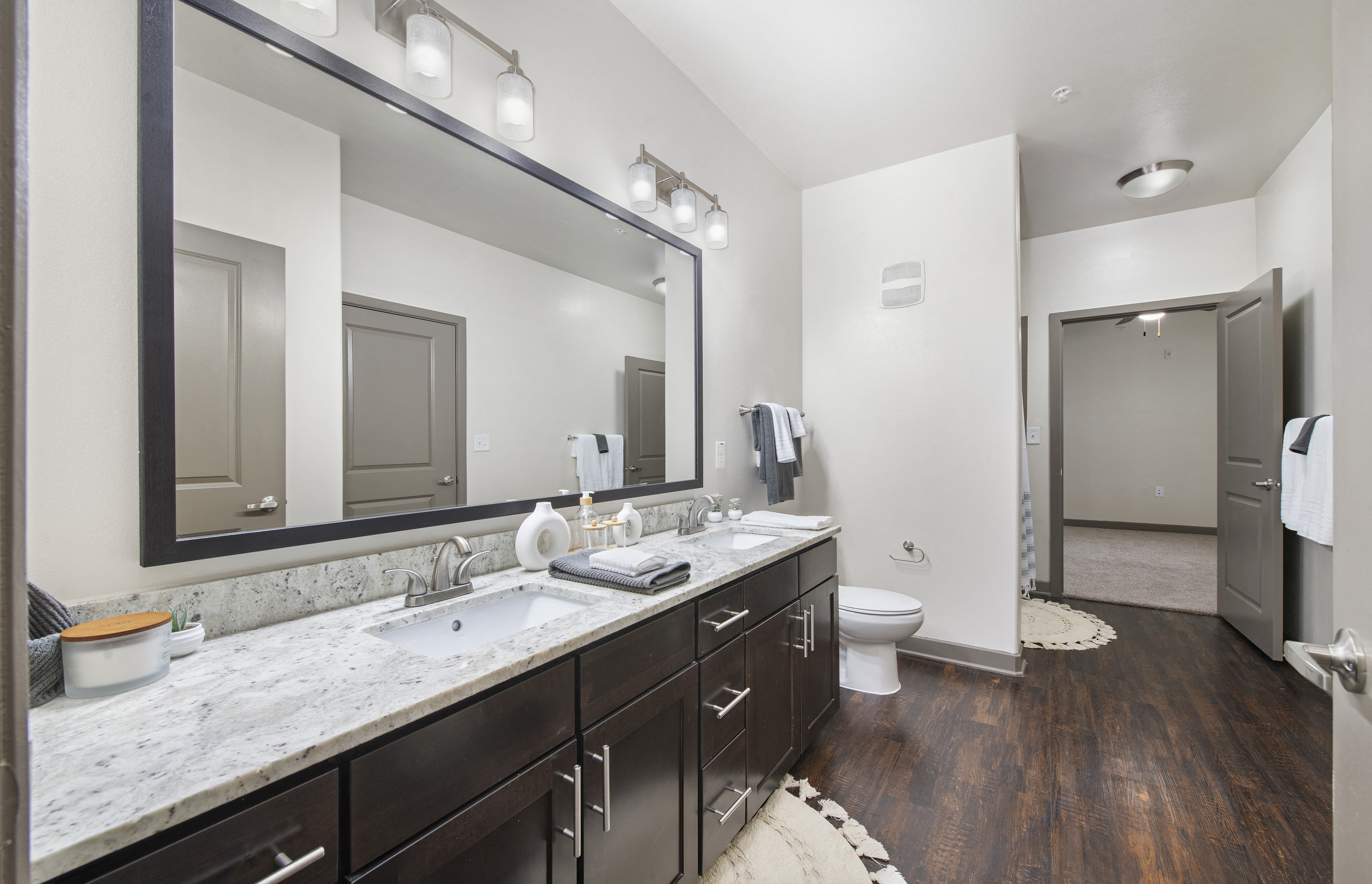 a bathroom with two sinks and a toilet and a large mirror