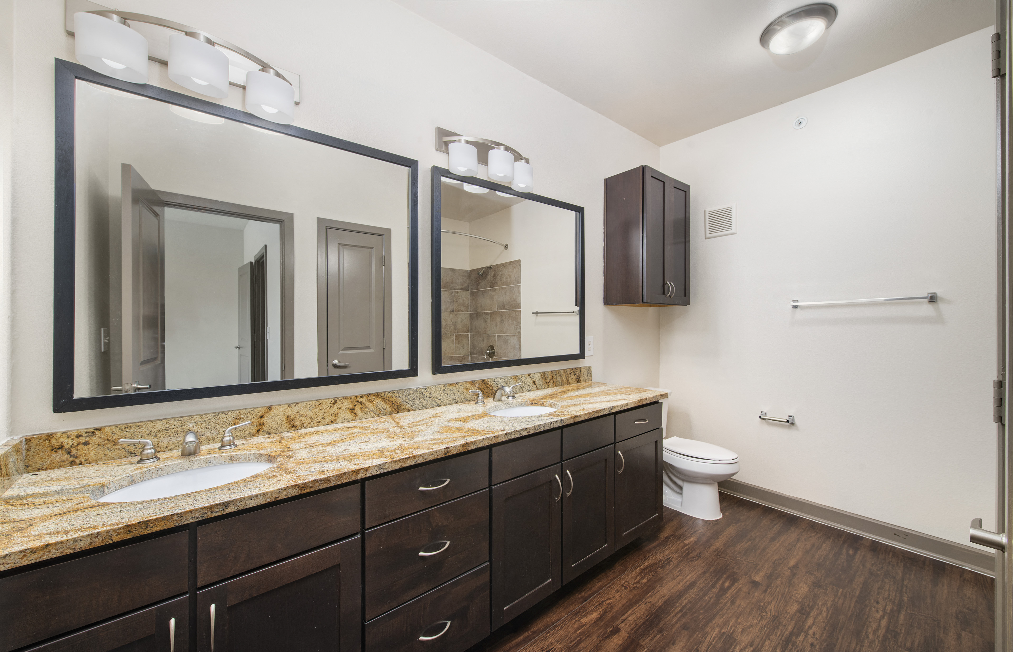 a bathroom with two sinks and two mirrors and a toilet