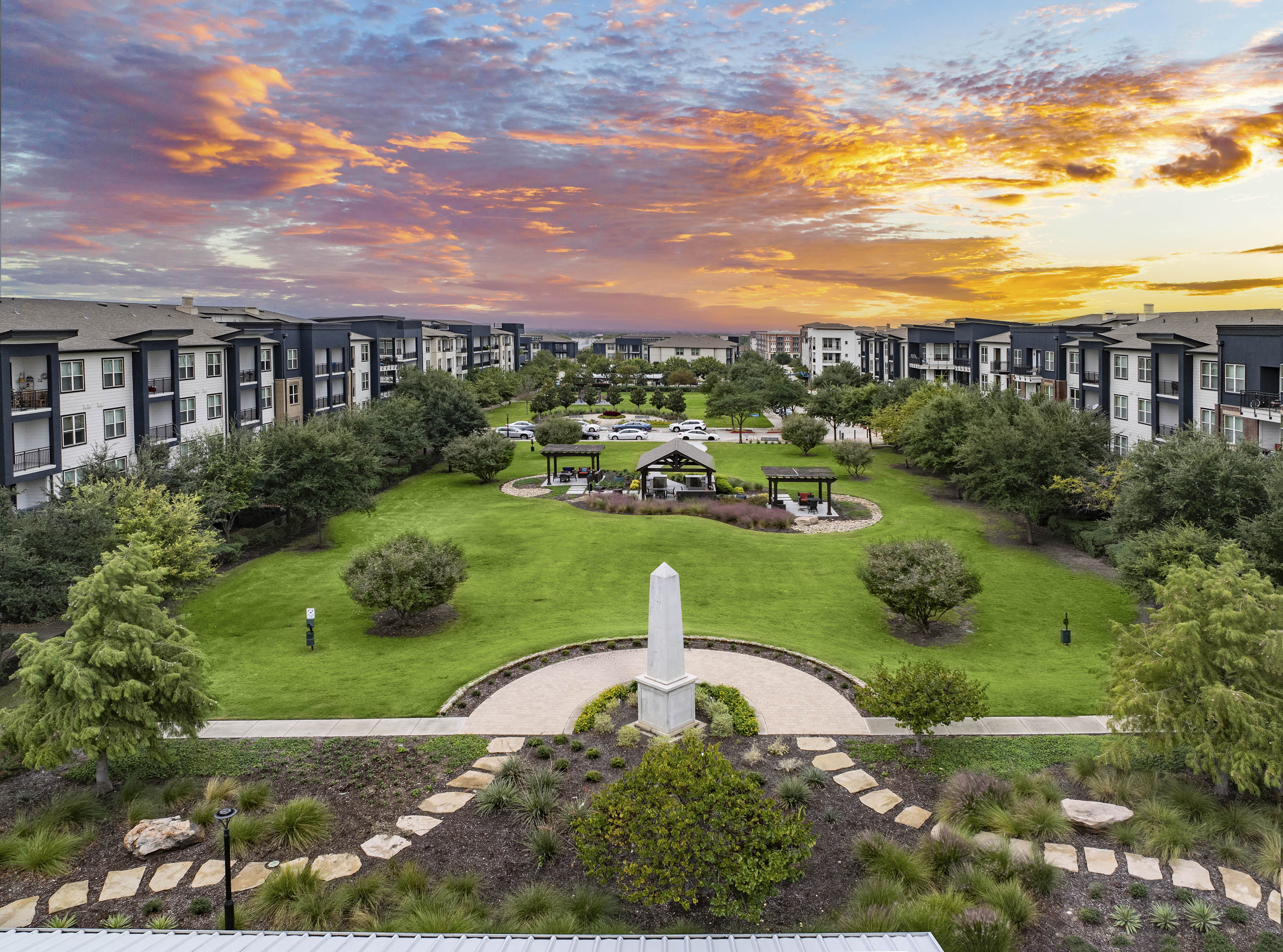 an aerial view of a park with a monument at sunset