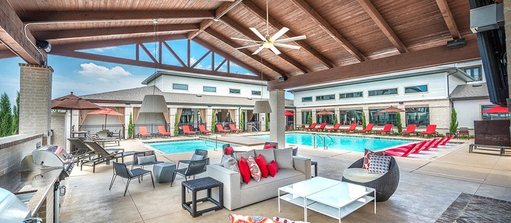 a swimming pool is under a covered patio with tables and chairs