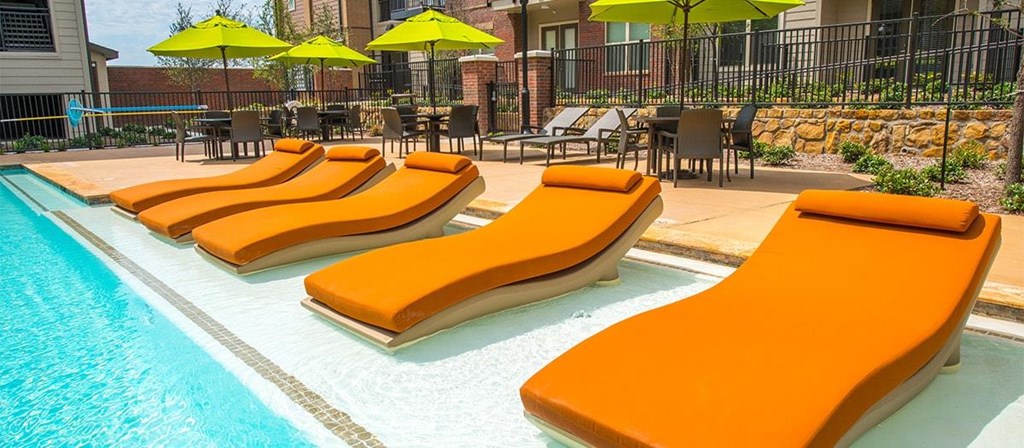 a group of orange lounge chairs next to a swimming pool