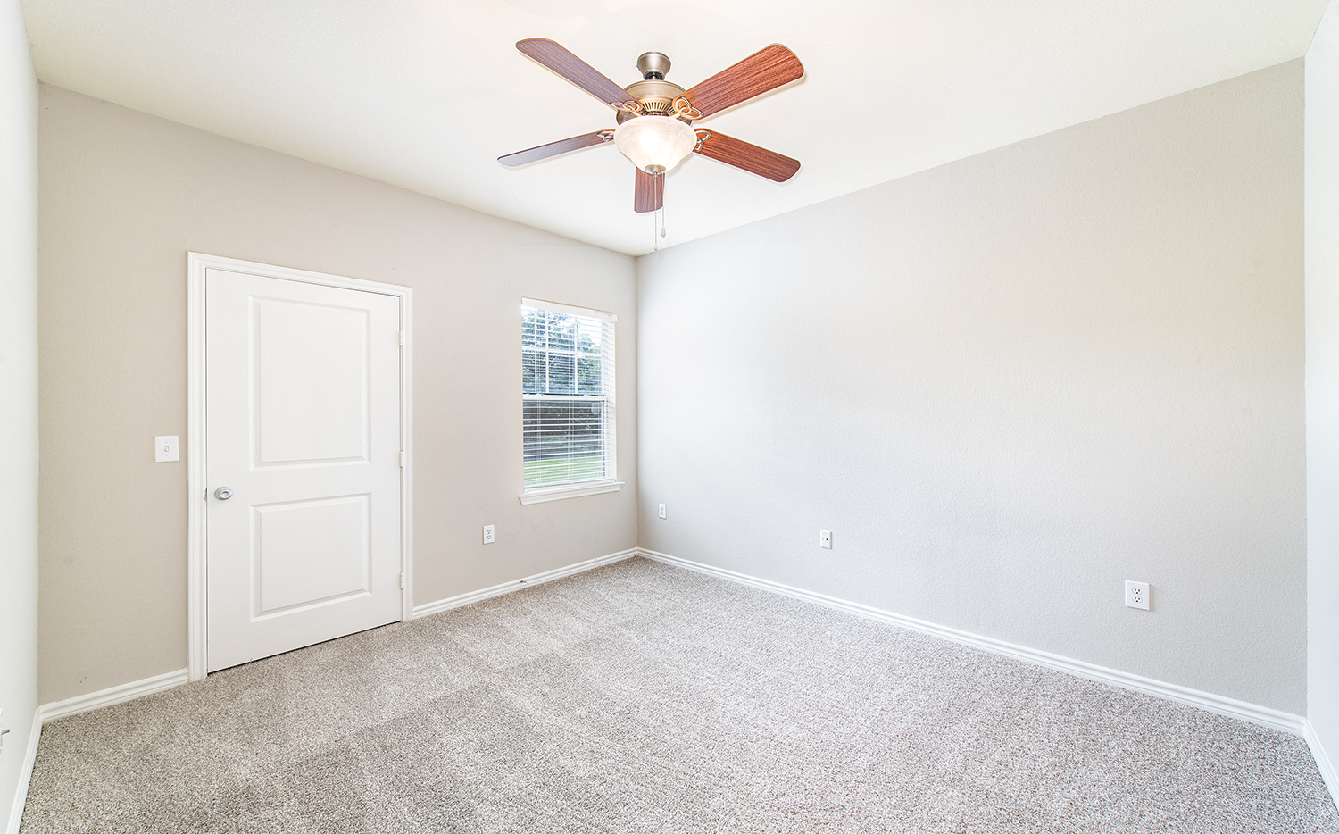 an empty room with a ceiling fan and a door