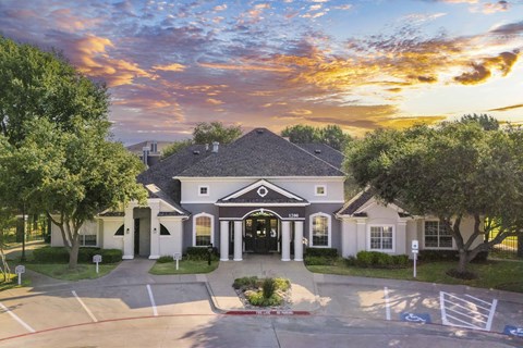 the front of a house with the sun setting behind it