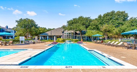 a pool with chairs and umbrellas and a house in the background