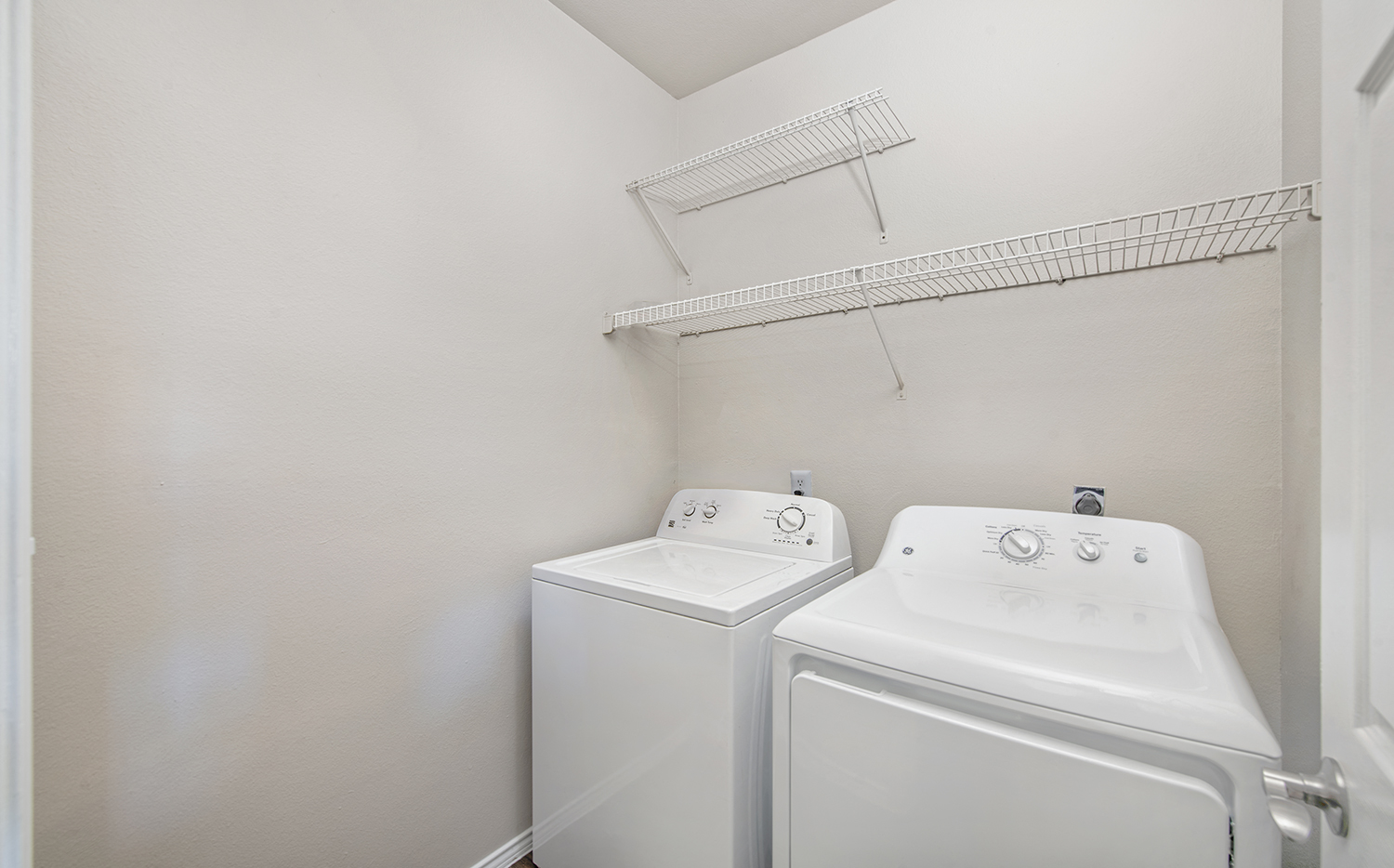 an empty laundry room with a washer and dryer and a white dryer