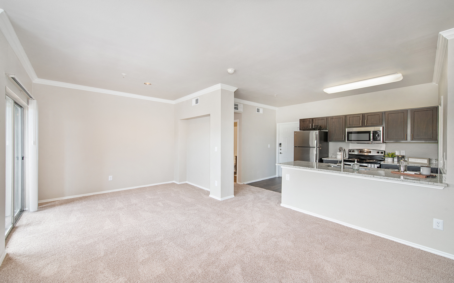an empty living room and kitchen with a counter top refrigerator and microwave