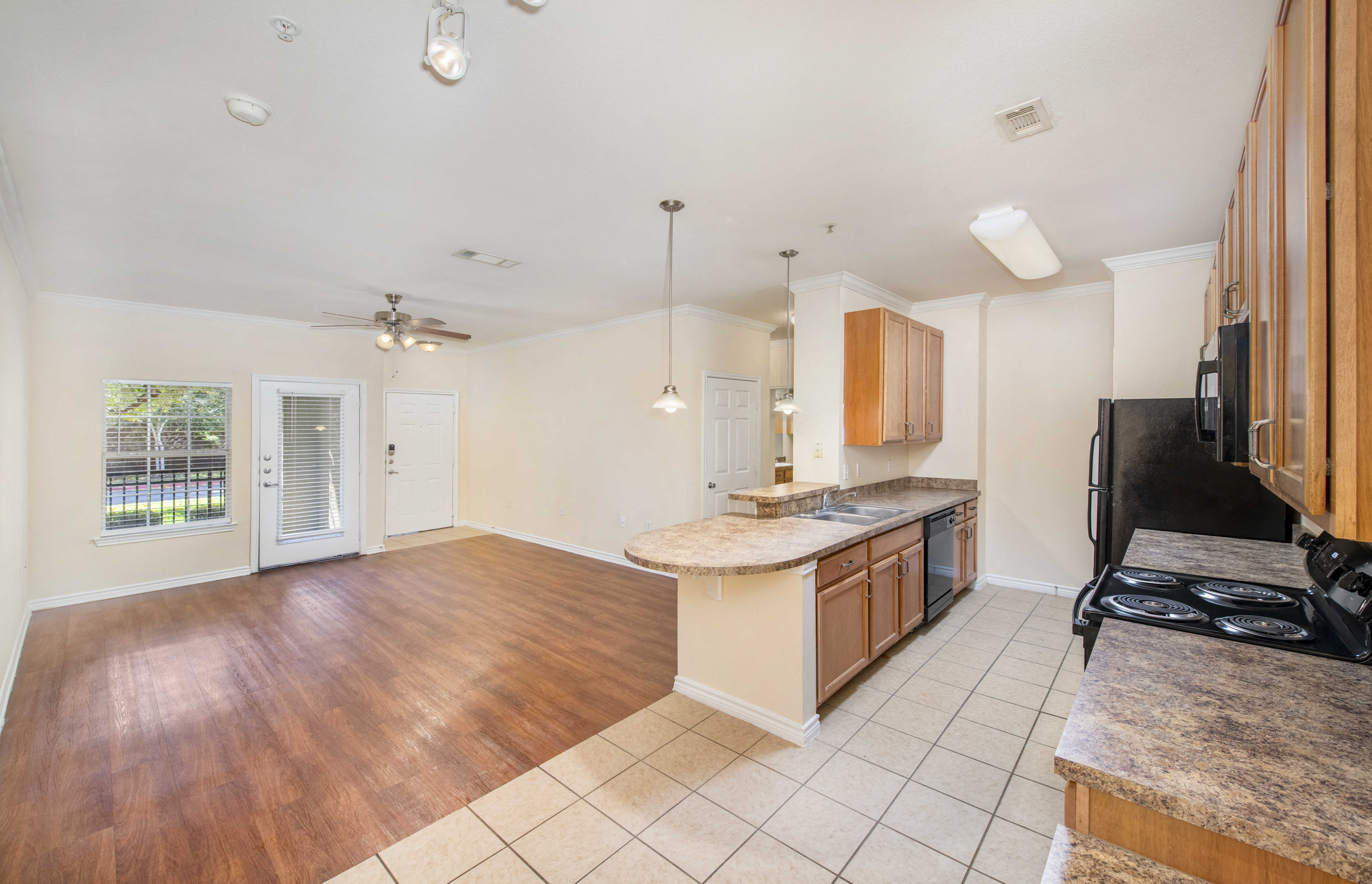an open kitchen and living room with a hardwood floor and a large window