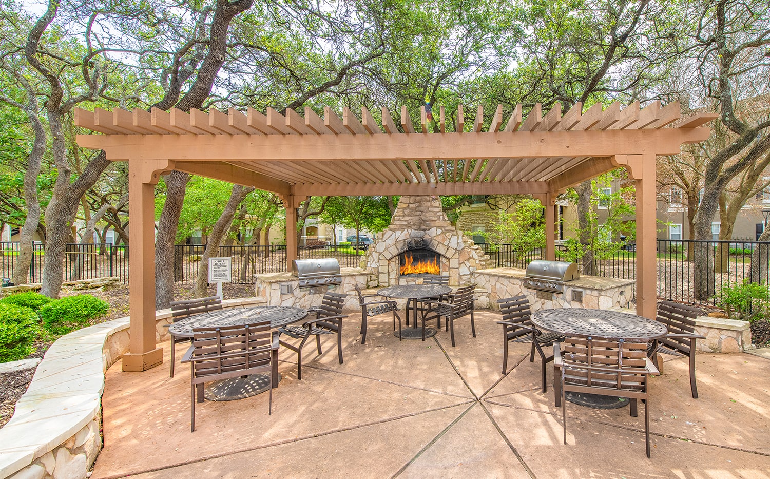a patio with a stone fireplace and tables and chairs