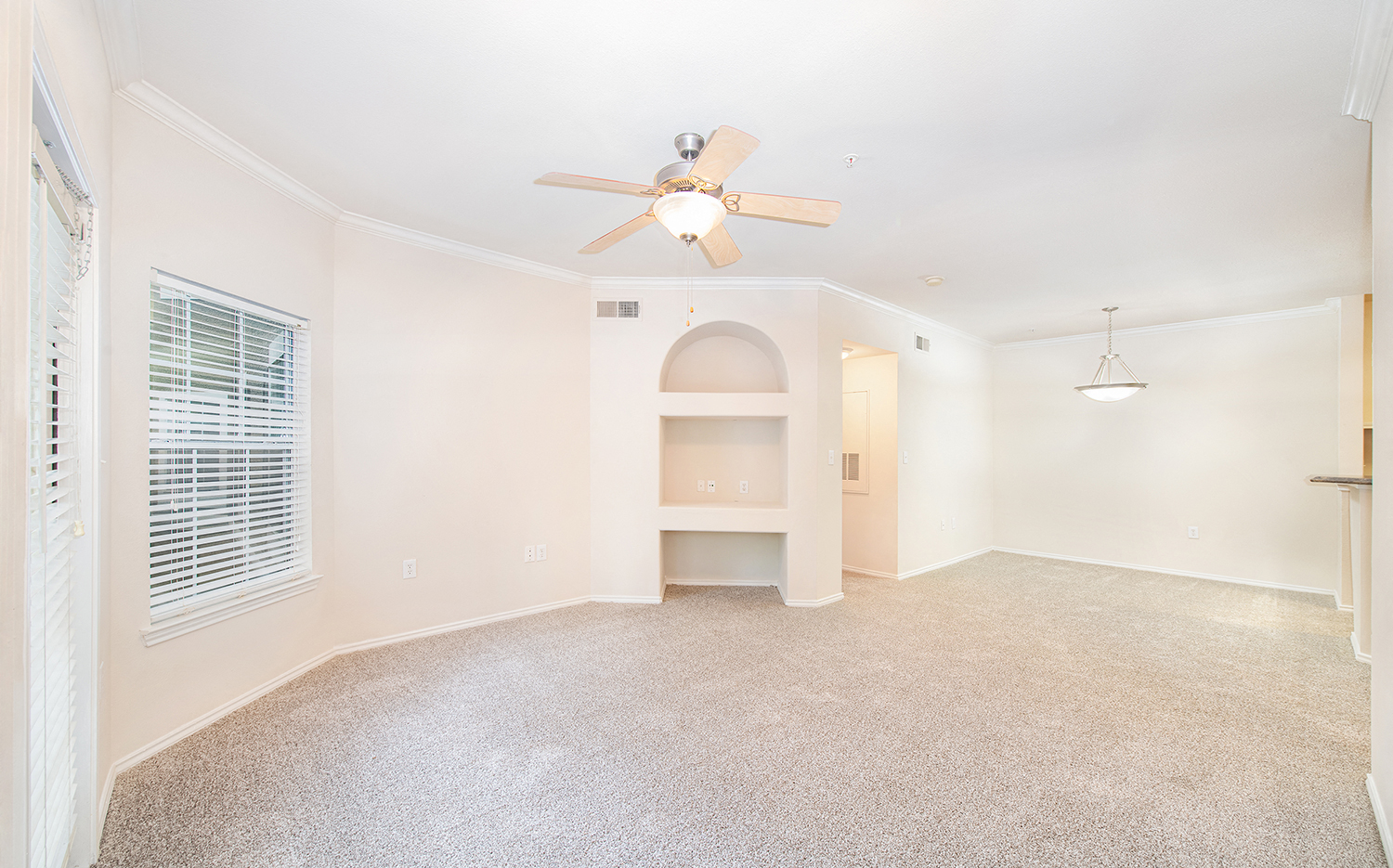 an empty living room with a ceiling fan and a window
