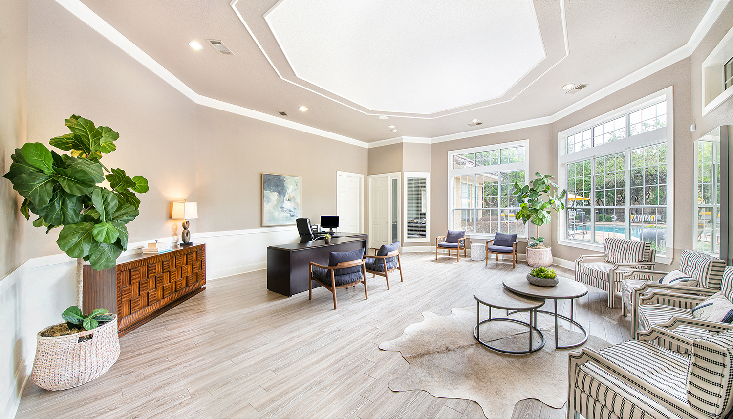 a living room with a desk and chairs and a large window