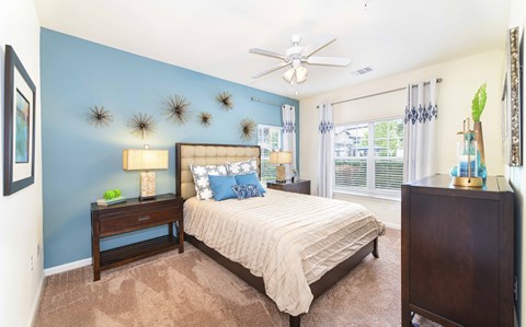 A bedroom with a bed, nightstand, and a ceiling fan.