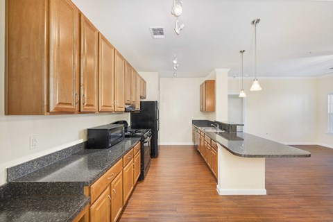 A kitchen with wooden cabinets and black countertops.
