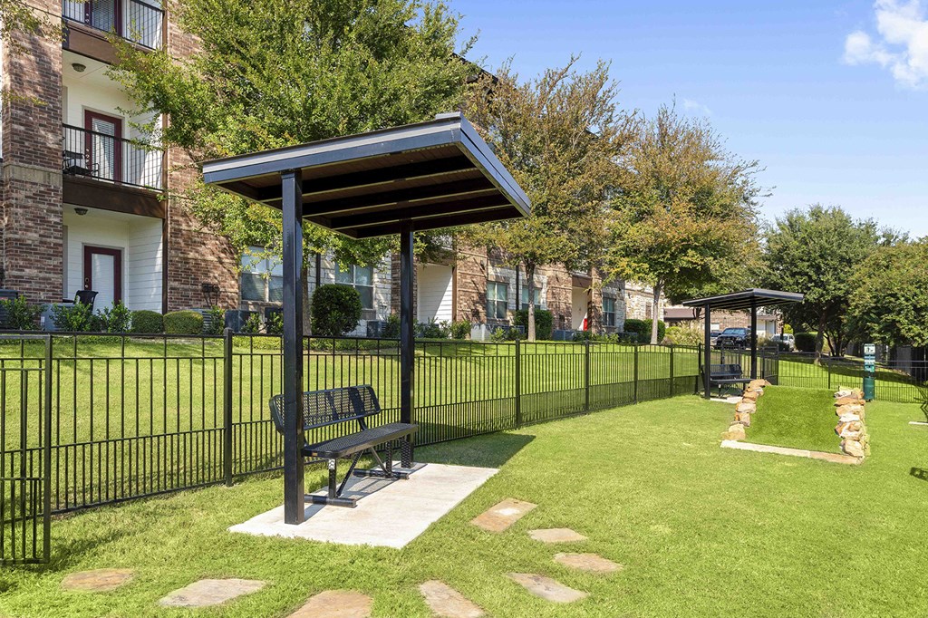 A bench under a canopy sits in a grassy area.