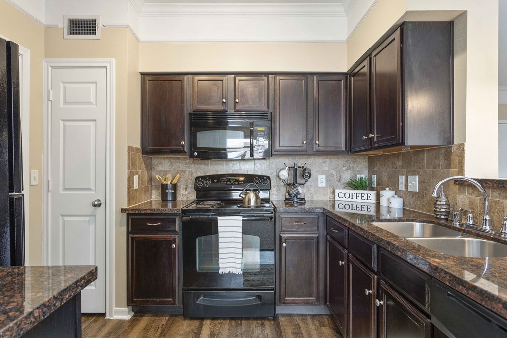 A kitchen with a black stove top oven and black cabinets.