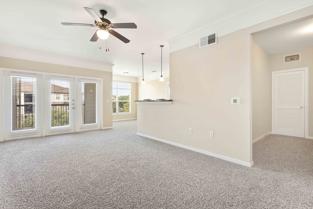 A spacious room with a ceiling fan and carpeted floor.