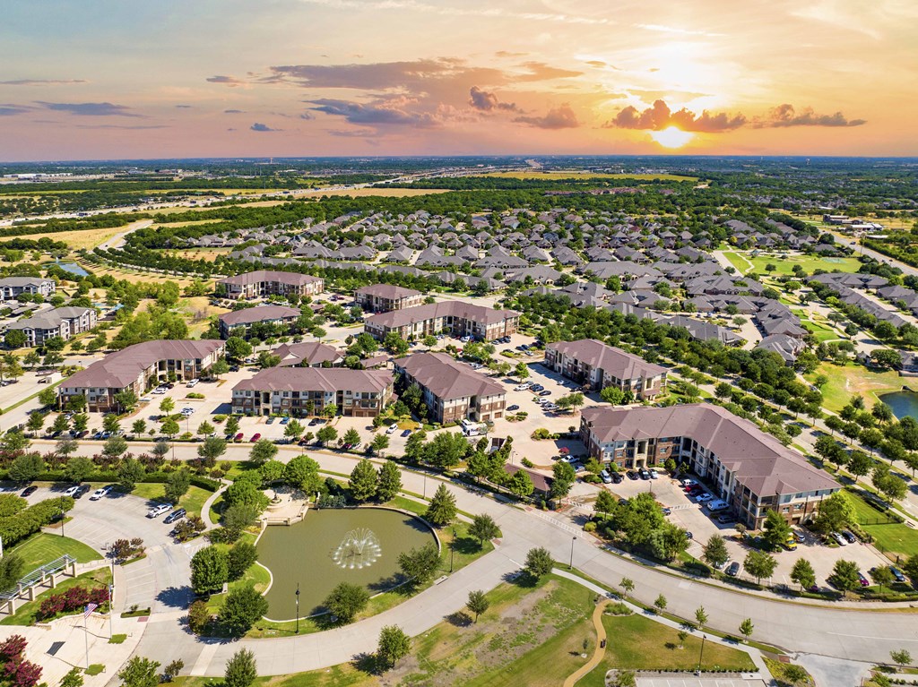 A sunset view of a residential area with houses and a park.