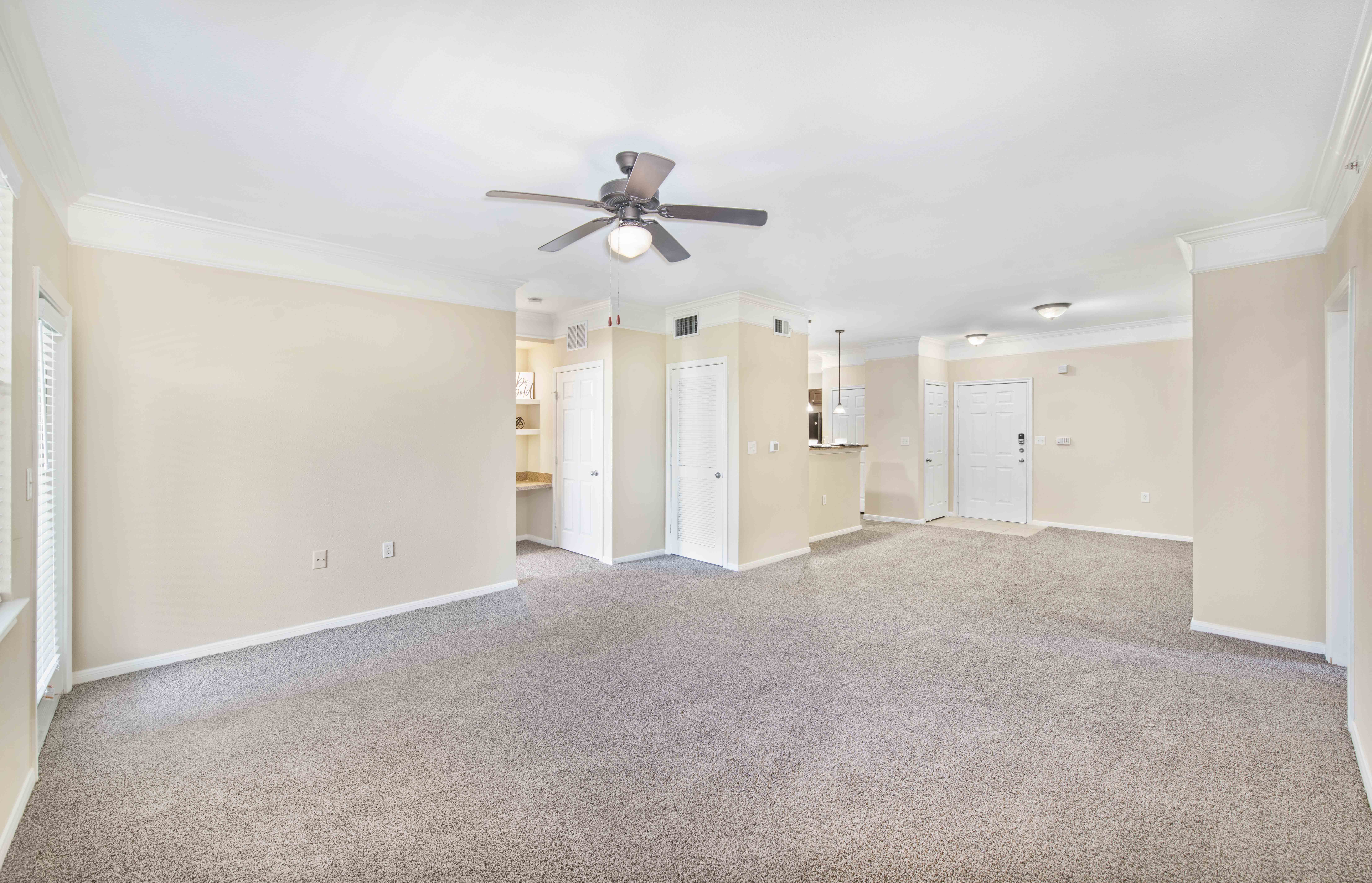 an empty living room with a ceiling fan