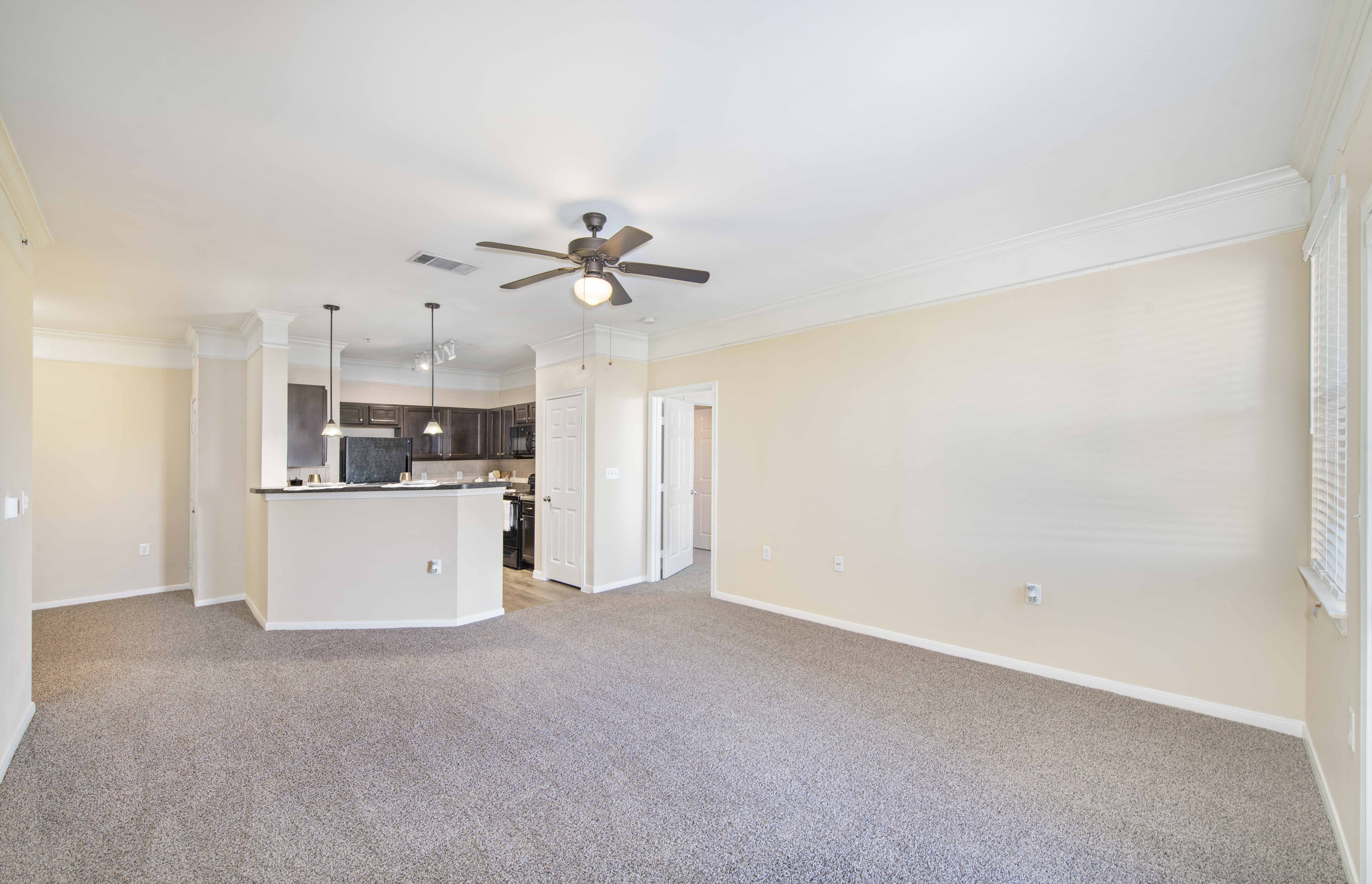 an empty living room and kitchen with a ceiling fan