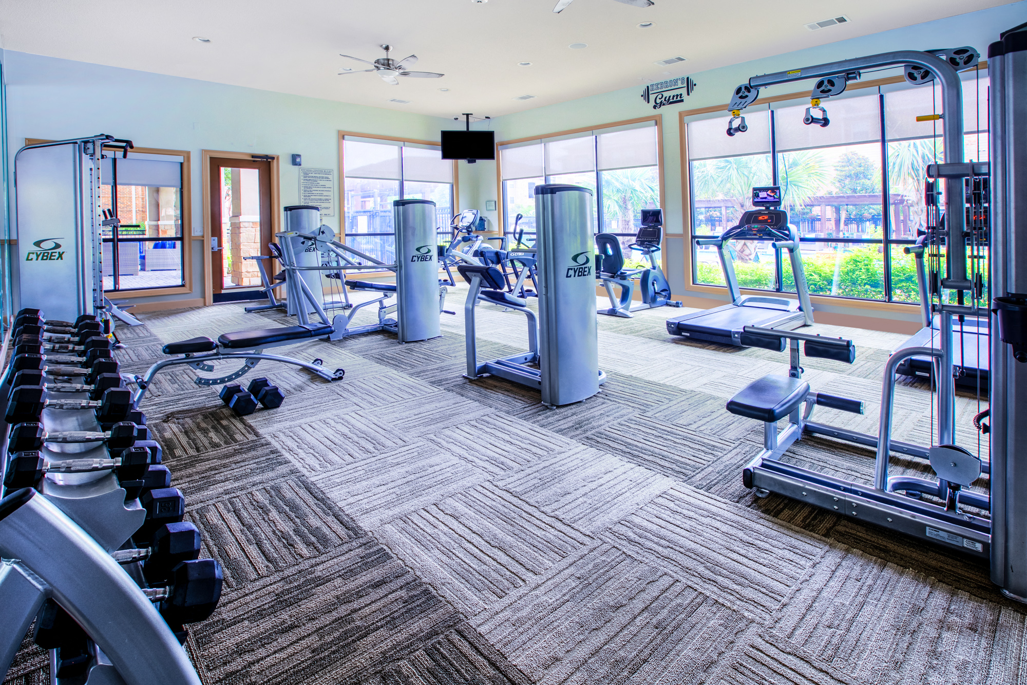 a gym with cardio equipment and windows with views of the outdoors