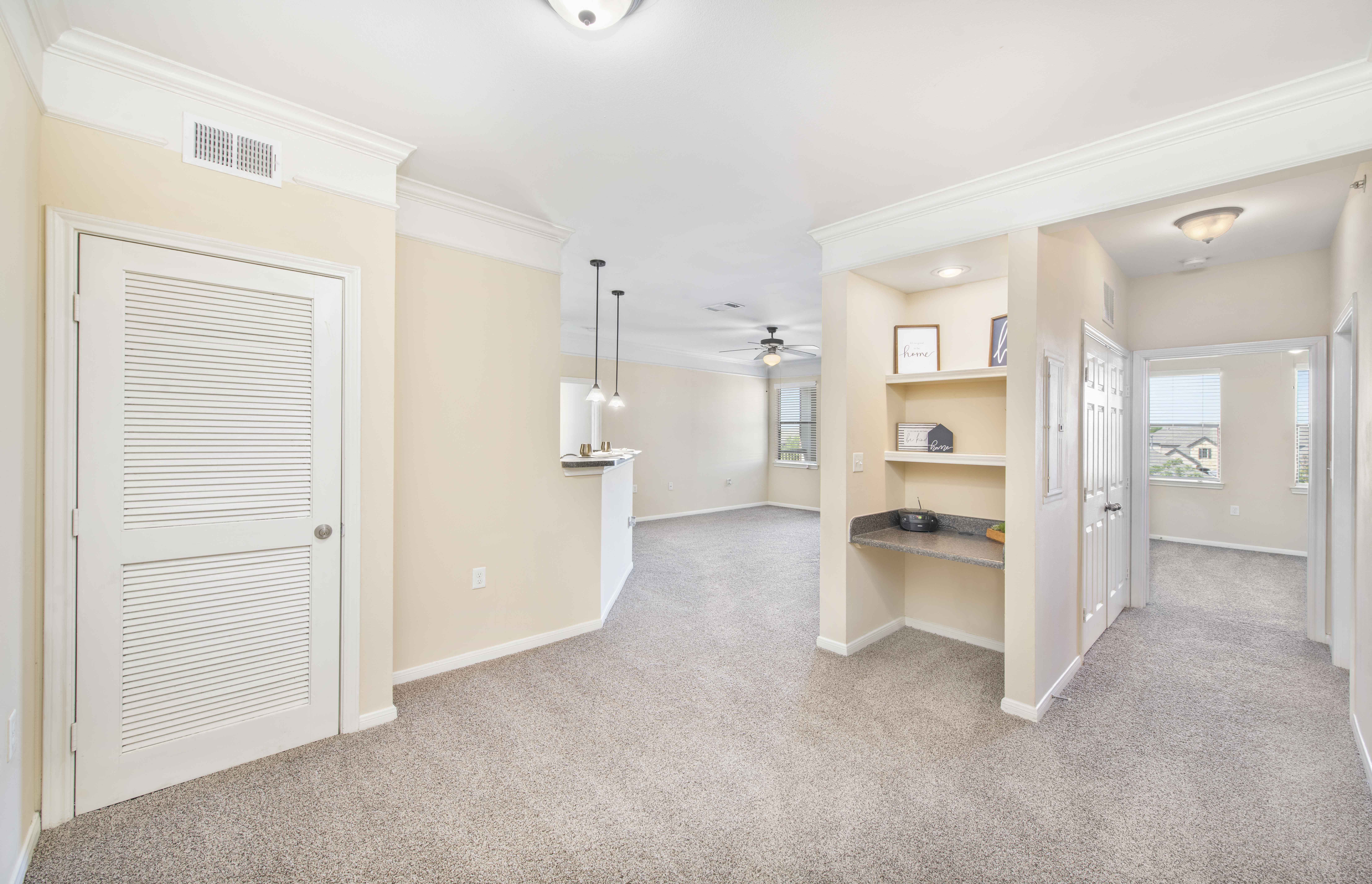 the living room and entryway of an empty home with a white door