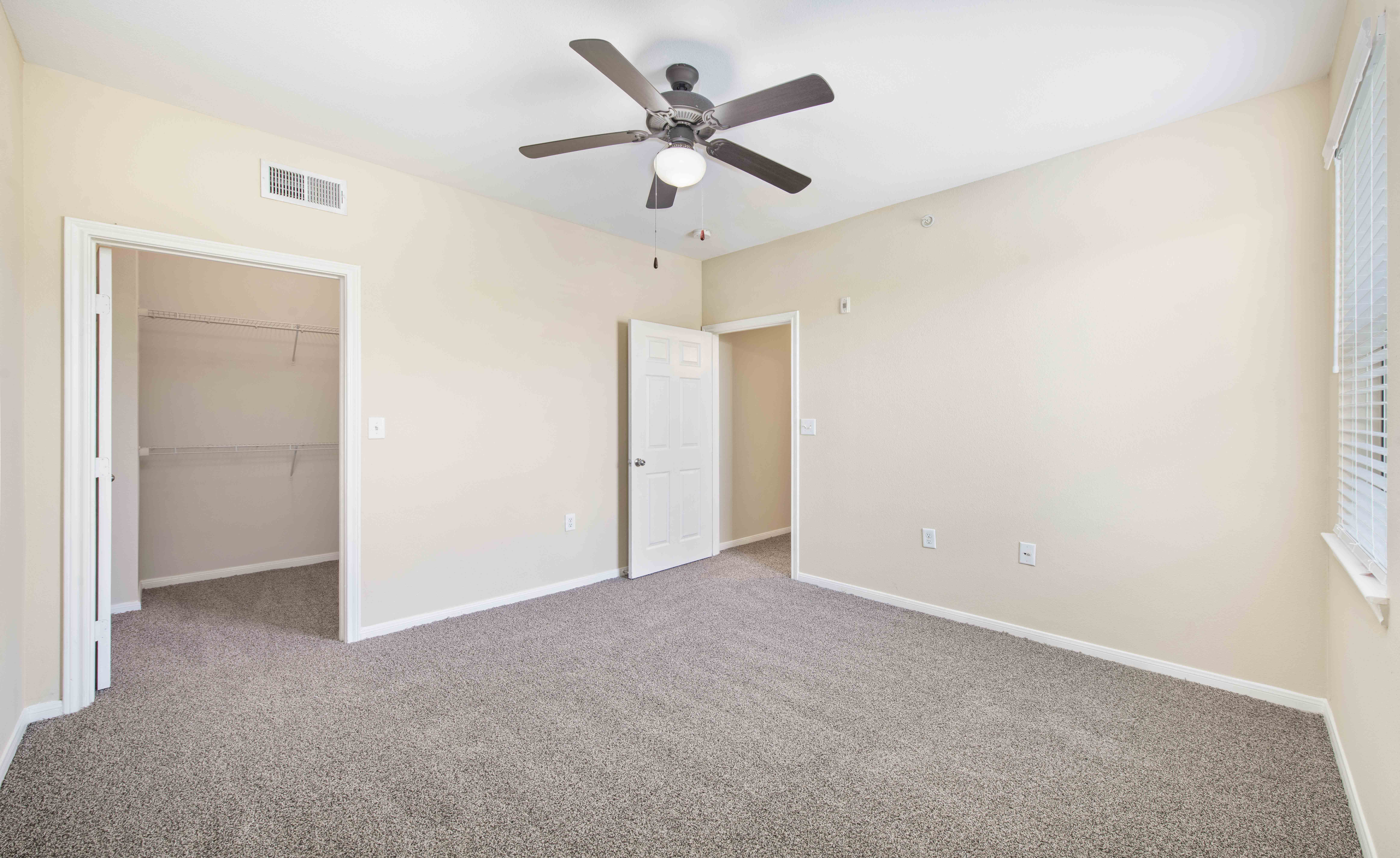 an empty room with a ceiling fan and a closet