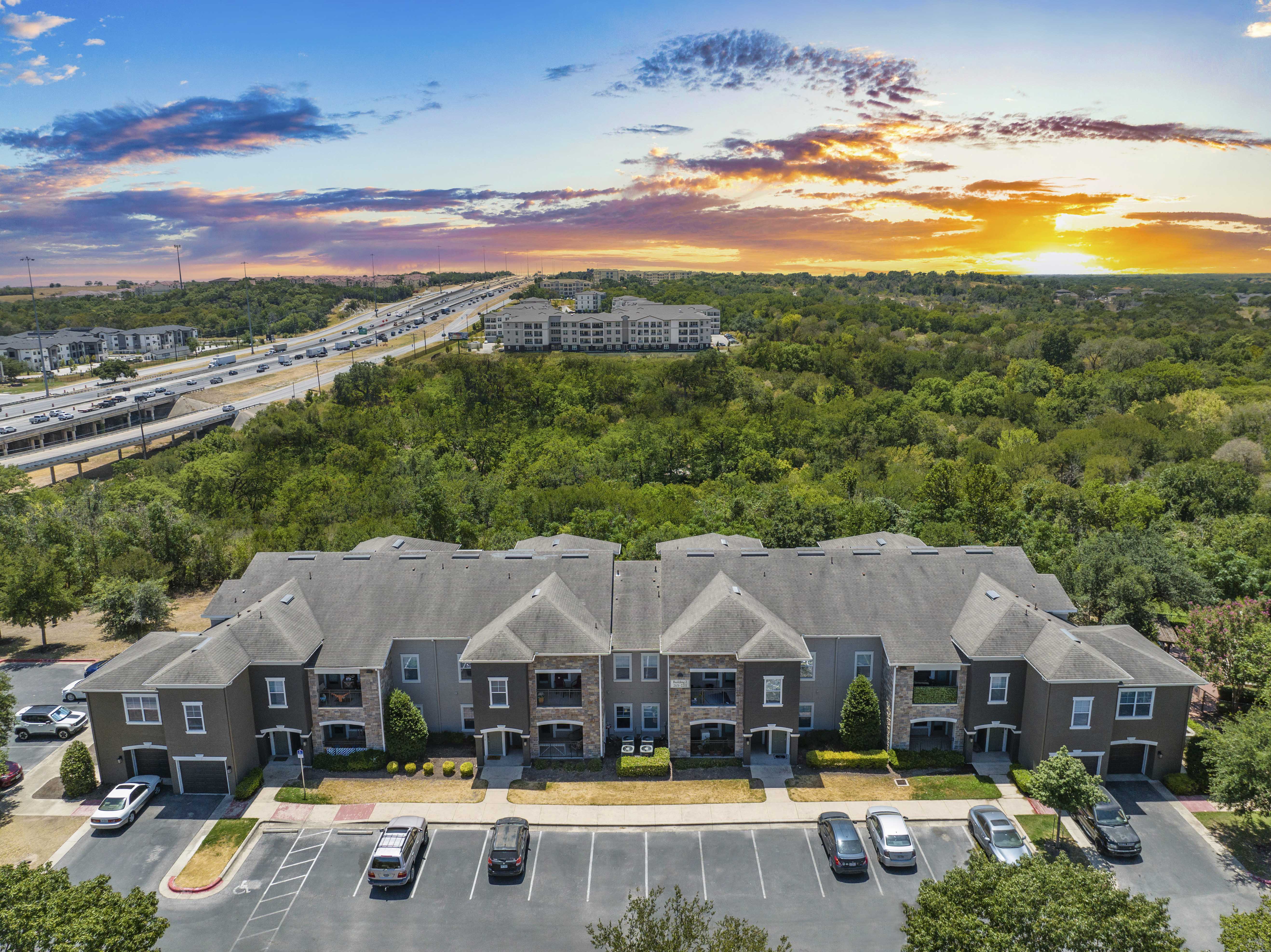 an aerial view of an apartment complex with a sunset in the background
