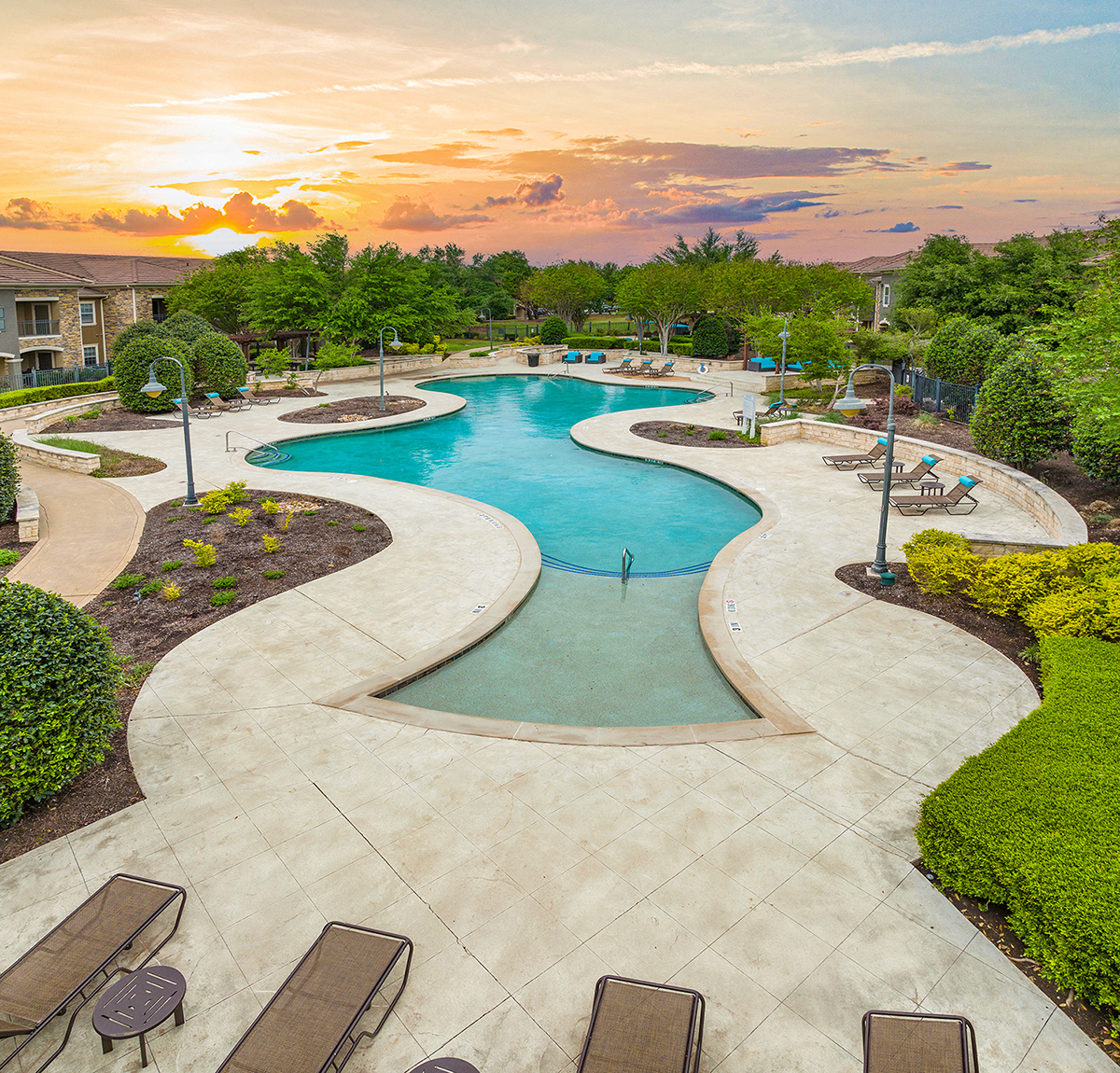 an aerial view of a swimming pool with a sunset in the background