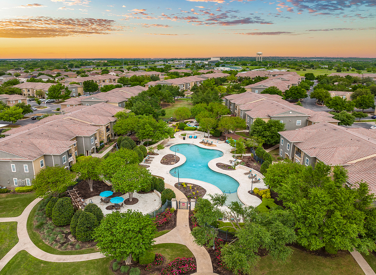 an aerial view of the resort style pool and community at sunset