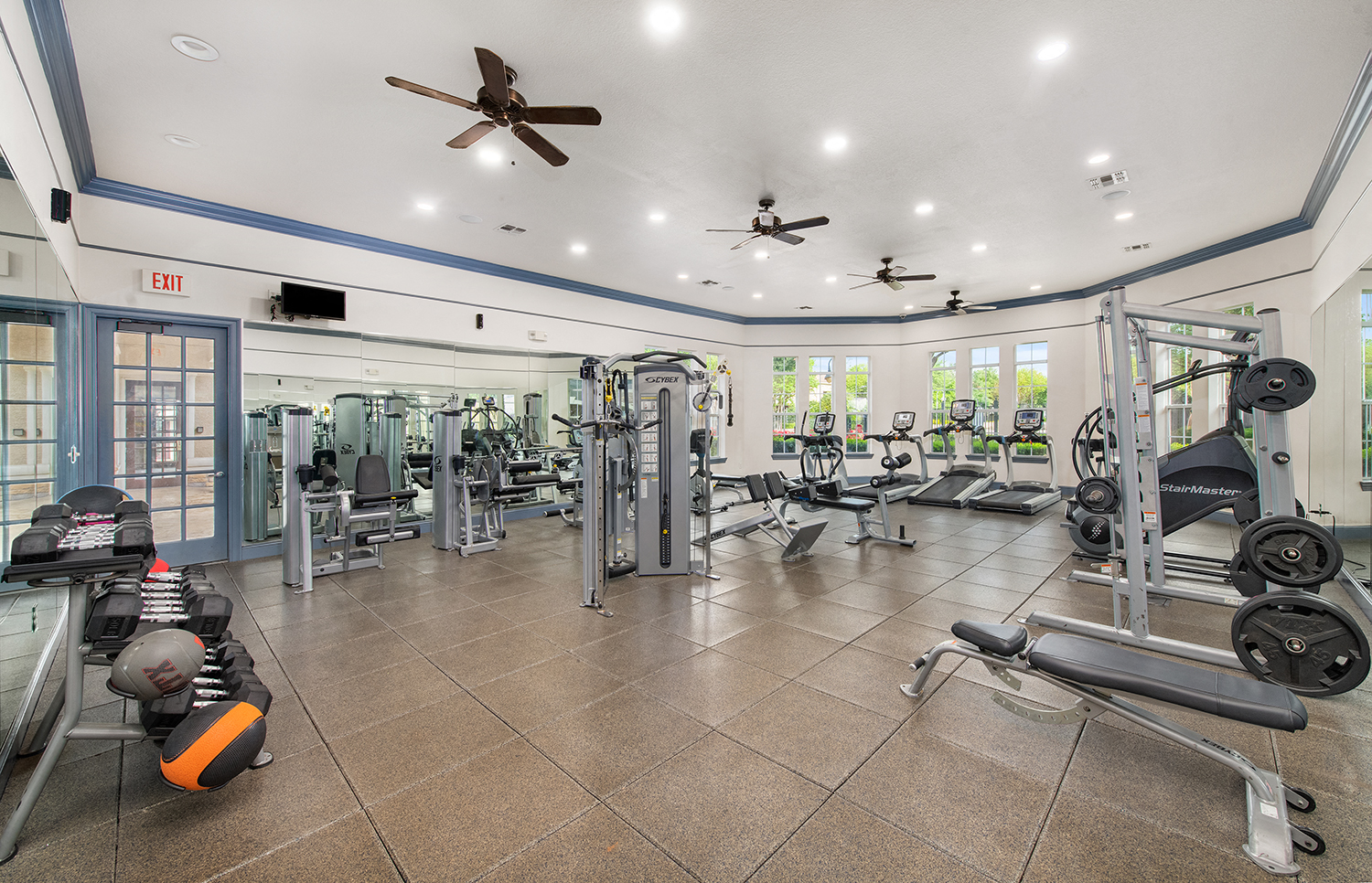a gym with weights and cardio equipment and ceiling fans